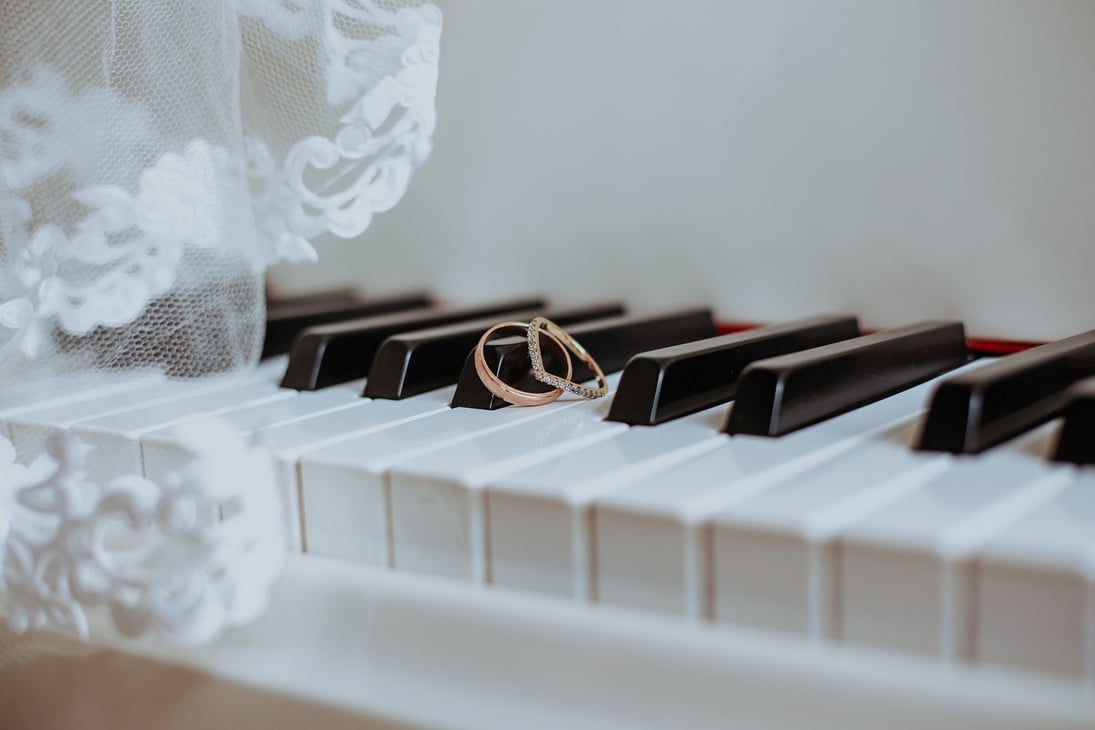 Wedding rings on piano keyboard under veil